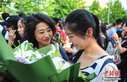 资料图：山东济南众多考生手捧鲜花在家长的簇拥下欢快告别高考。中新社记者 张勇 摄