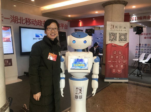 1月13日，政协湖北省十二届二次会议在洪山礼堂开幕。长江云机器人记者“云朵”，连续四年参与两会采访！图为参会委员与“云朵”互动。